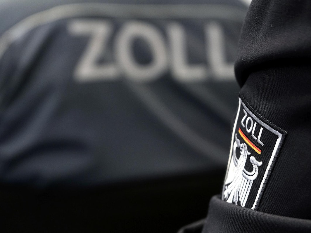 Auf Dienstbekleidung steht das Zoll-Emblem.