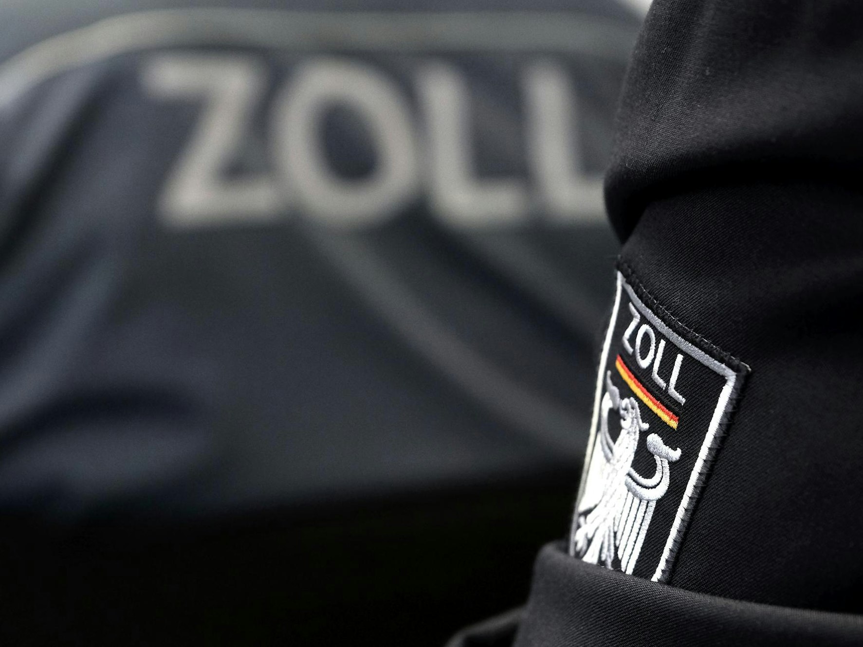Auf Dienstbekleidung steht das Zoll-Emblem.