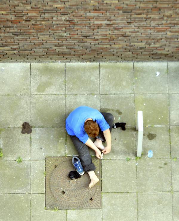 Heroin-Abhängige setzen sich auf dem Boden sitzend einen Schuss.