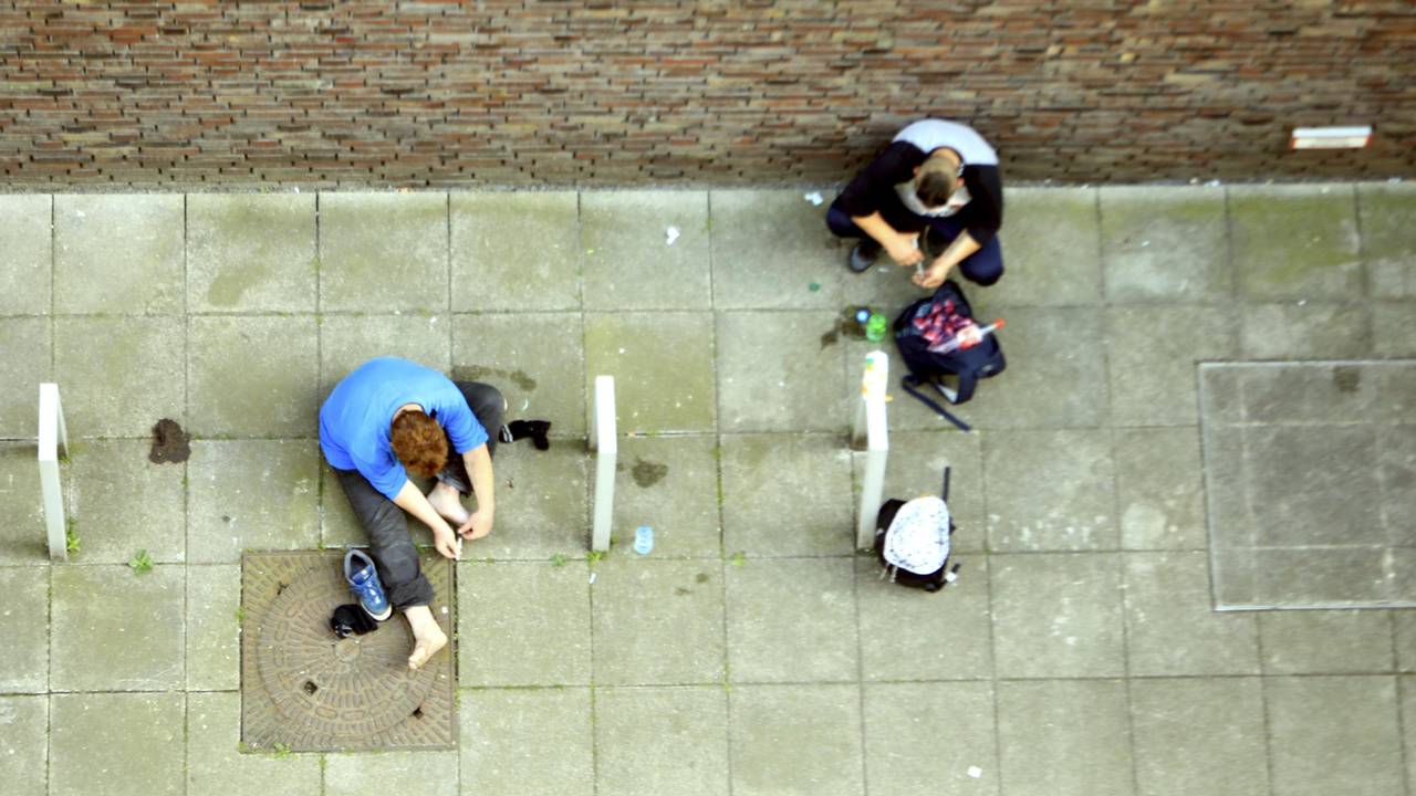 Heroin-Abhängige setzen sich auf dem Boden sitzend einen Schuss.