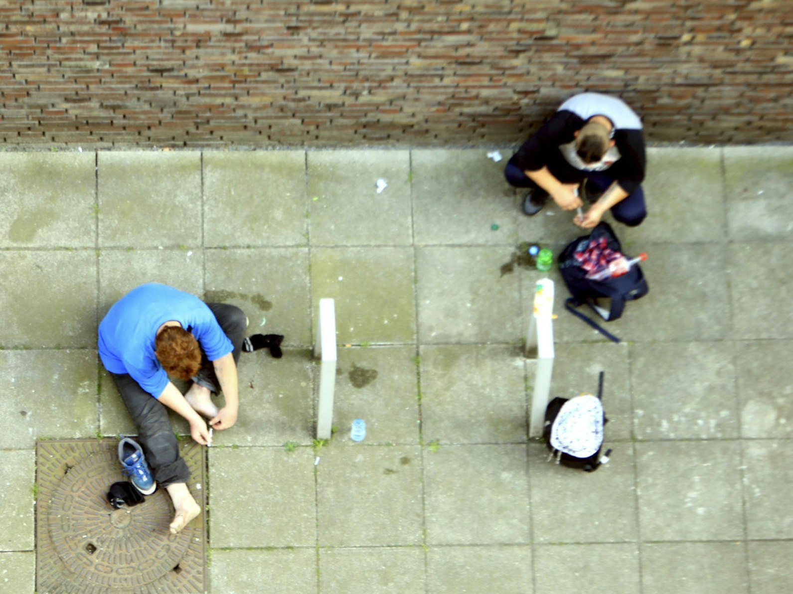 Heroin-Abhängige setzen sich auf dem Boden sitzend einen Schuss.