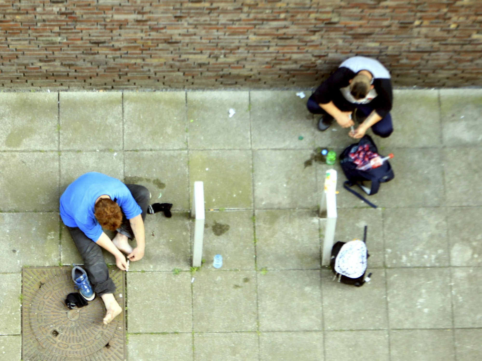 Heroin-Abhängige setzen sich auf dem Boden sitzend einen Schuss.