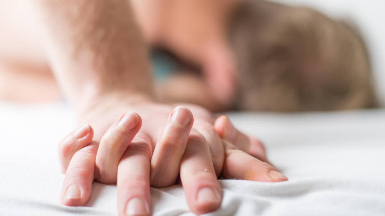 Paar knutscht im Bett und hält Händchen