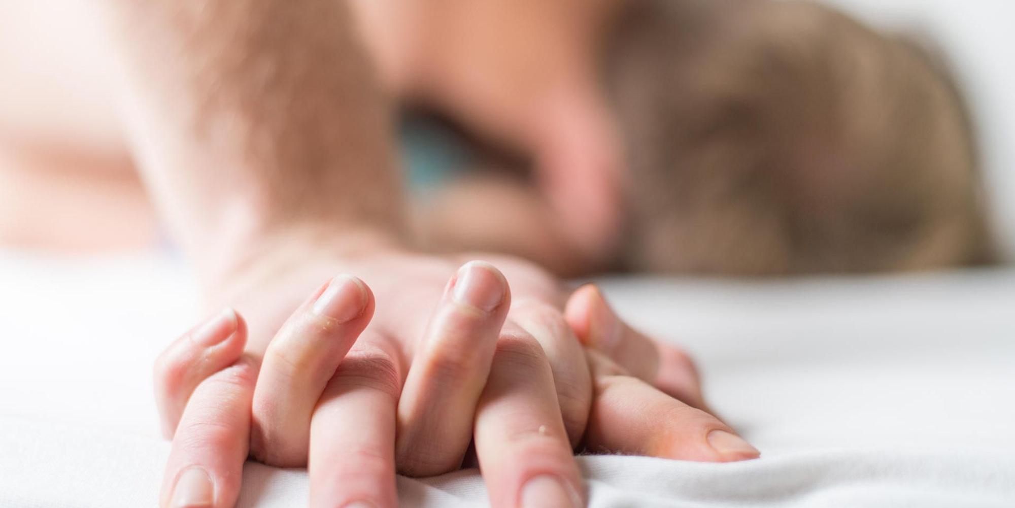 Paar knutscht im Bett und hält Händchen