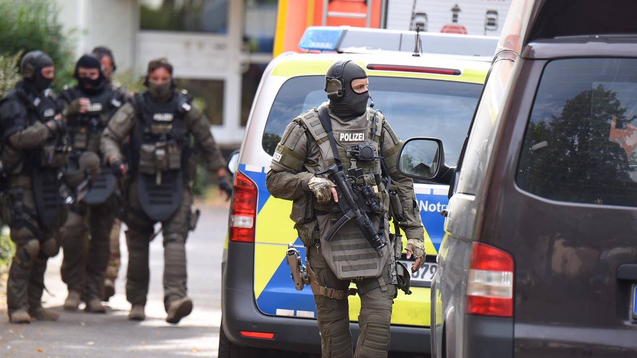 Bewaffnete Spezialkräfte bei einem Einsatz neben einem Polizeiwagen