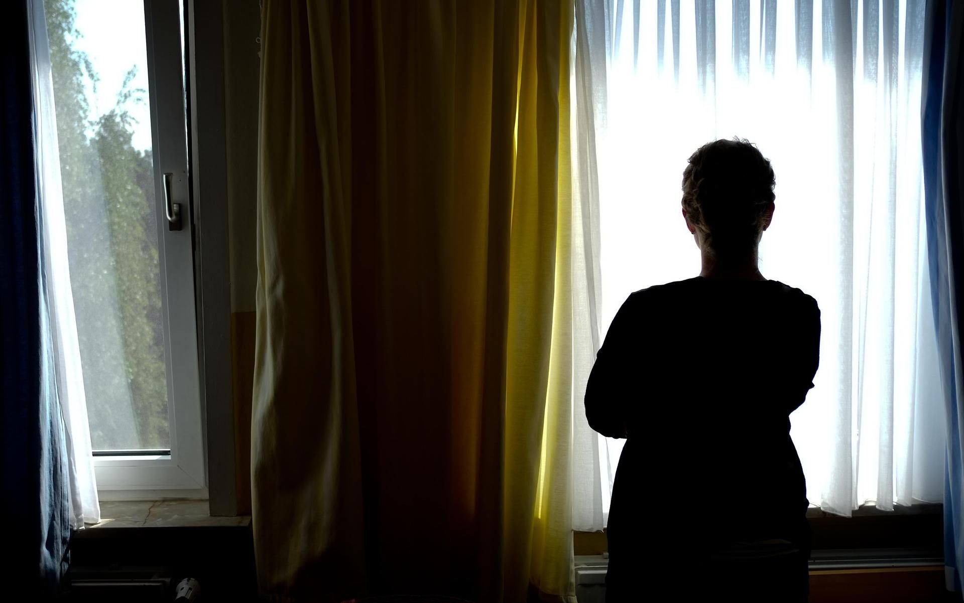 Eine Frau schaut nachdenklich aus dem Fenster.