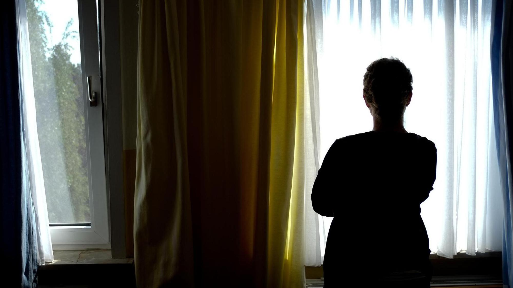 Eine Frau schaut nachdenklich aus dem Fenster.