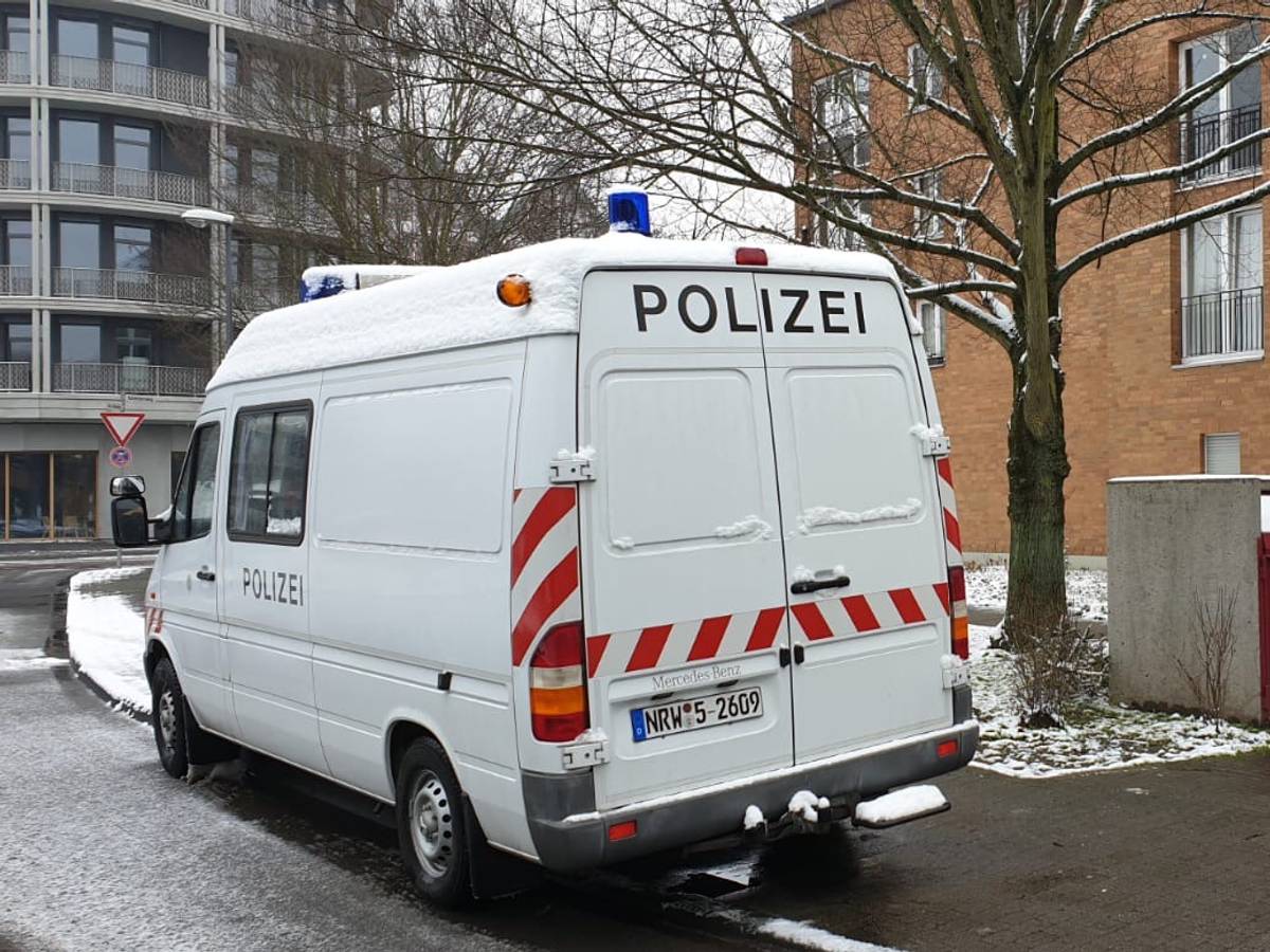 Ein Kastenwagen der Polizei steht vor einem Mehrfamilienhaus
