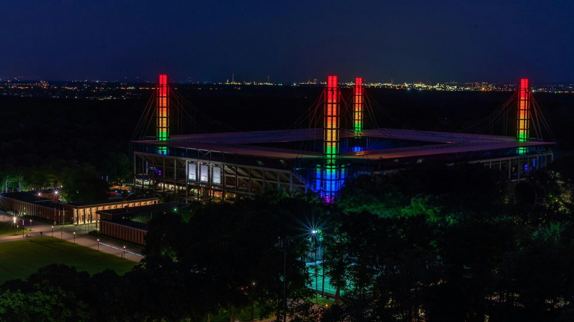Blick aus der Luft auf das Rhein-Energie-Stadion in Köln: Die Türme in den Ecken sind bunt erleuchtet.