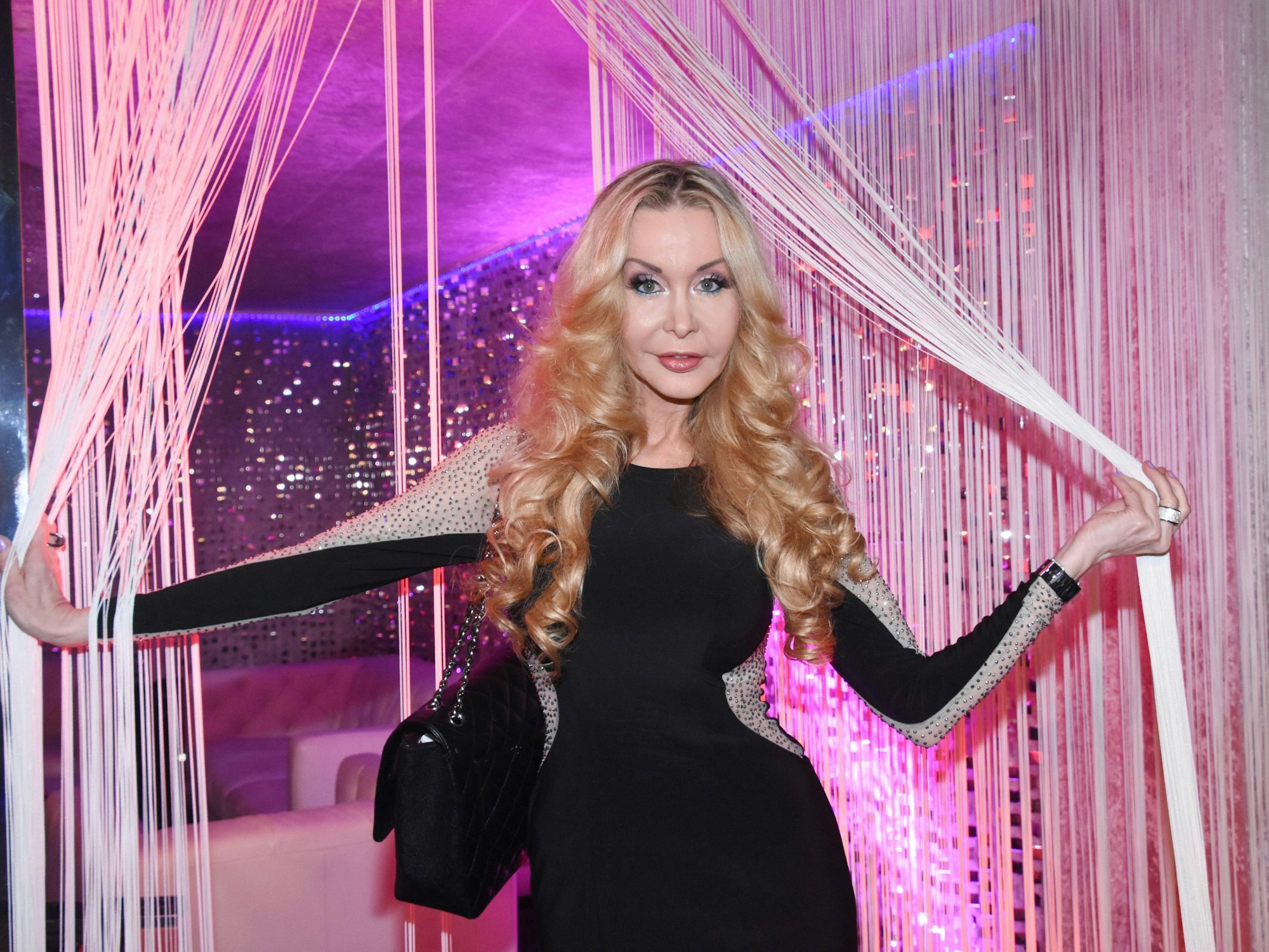 Dolly Buster tritt durch einen Vorhang in einer Bar.