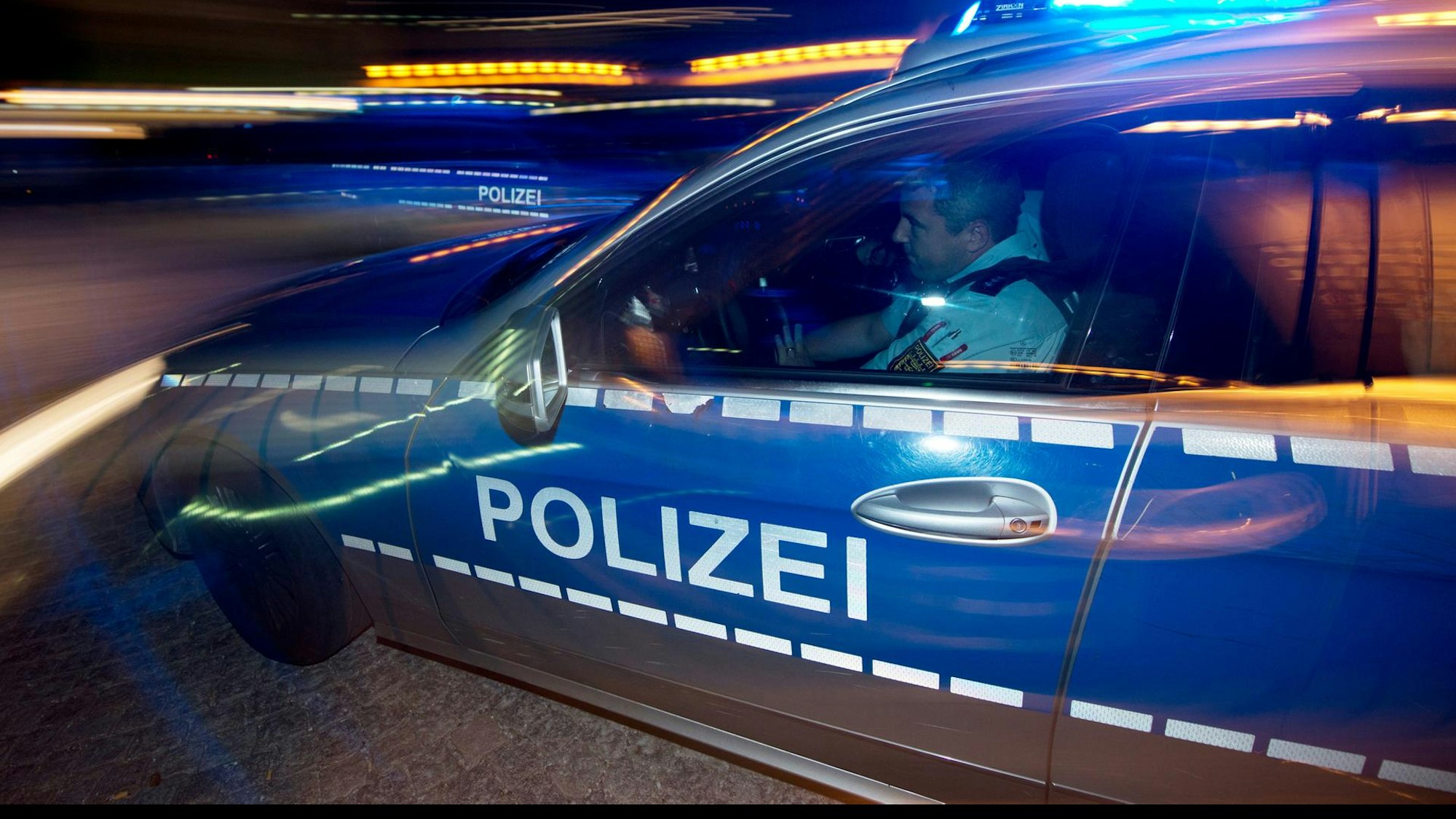 Ein Polizeiauto fährt nachts mit Blaulicht. (Symbolfoto)