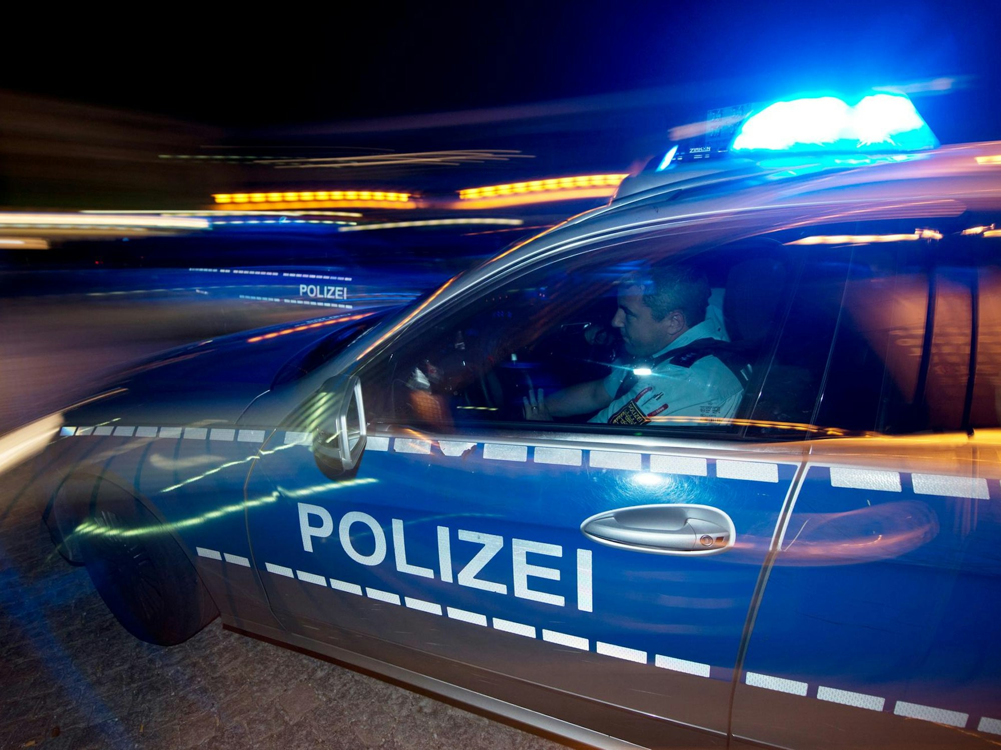 Ein Polizist sitzt in einem Streifenwagen.