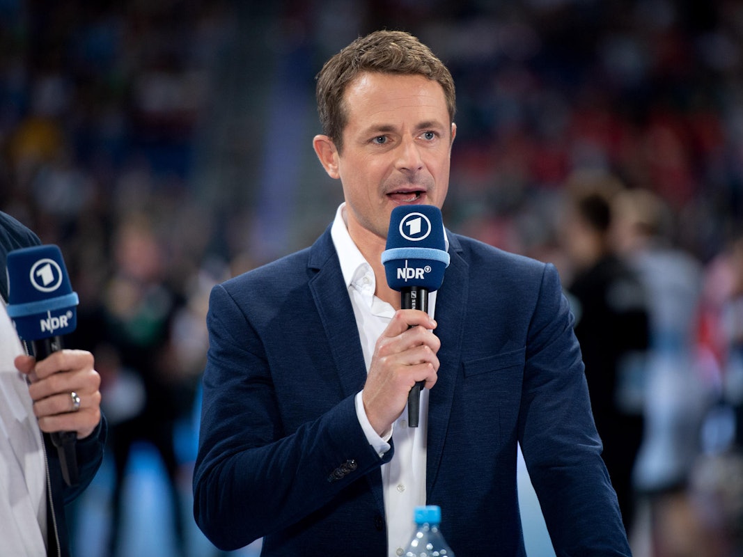 Alexander Bommes moderiert bei einer EM-Übertragung mit einem Mikrofon in der Hand..