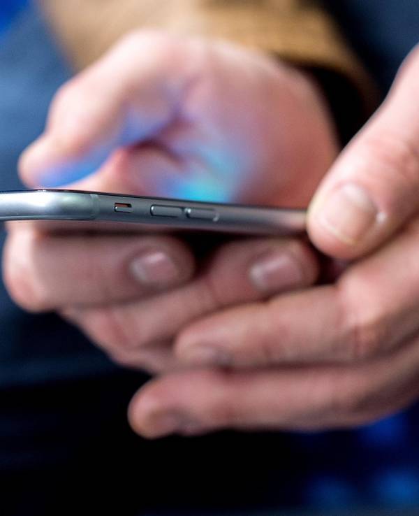 Mann hält ein Smartphone in der Hand.