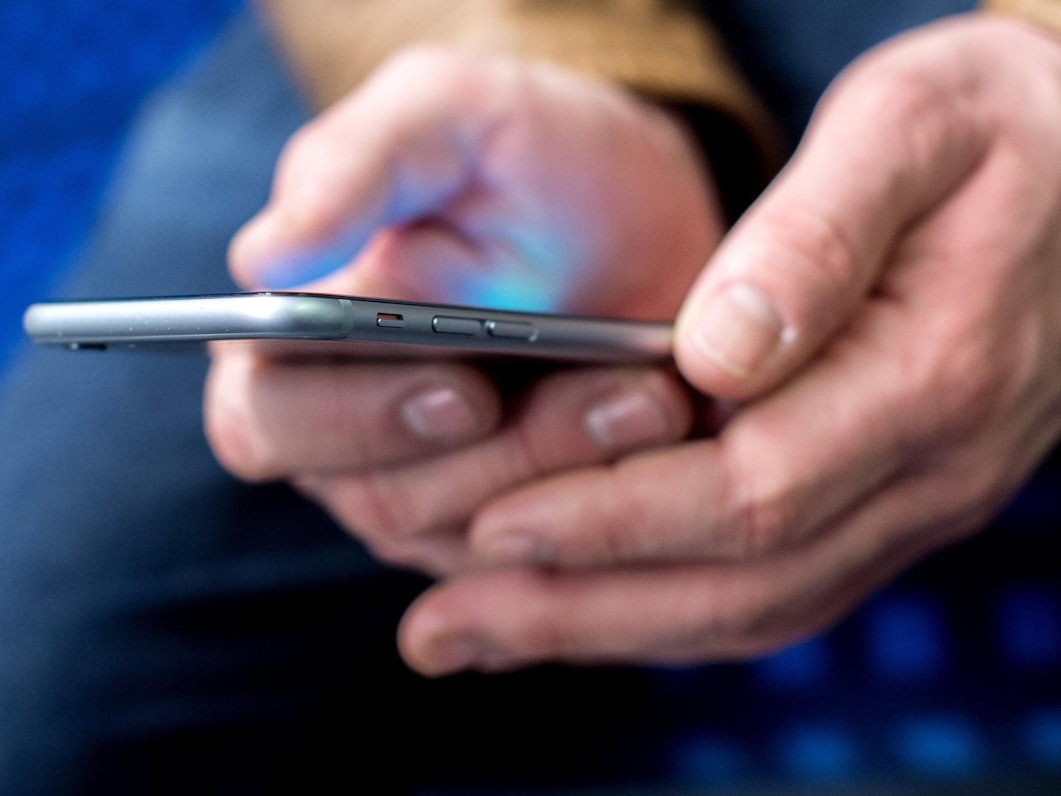 Mann hält ein Smartphone in der Hand.