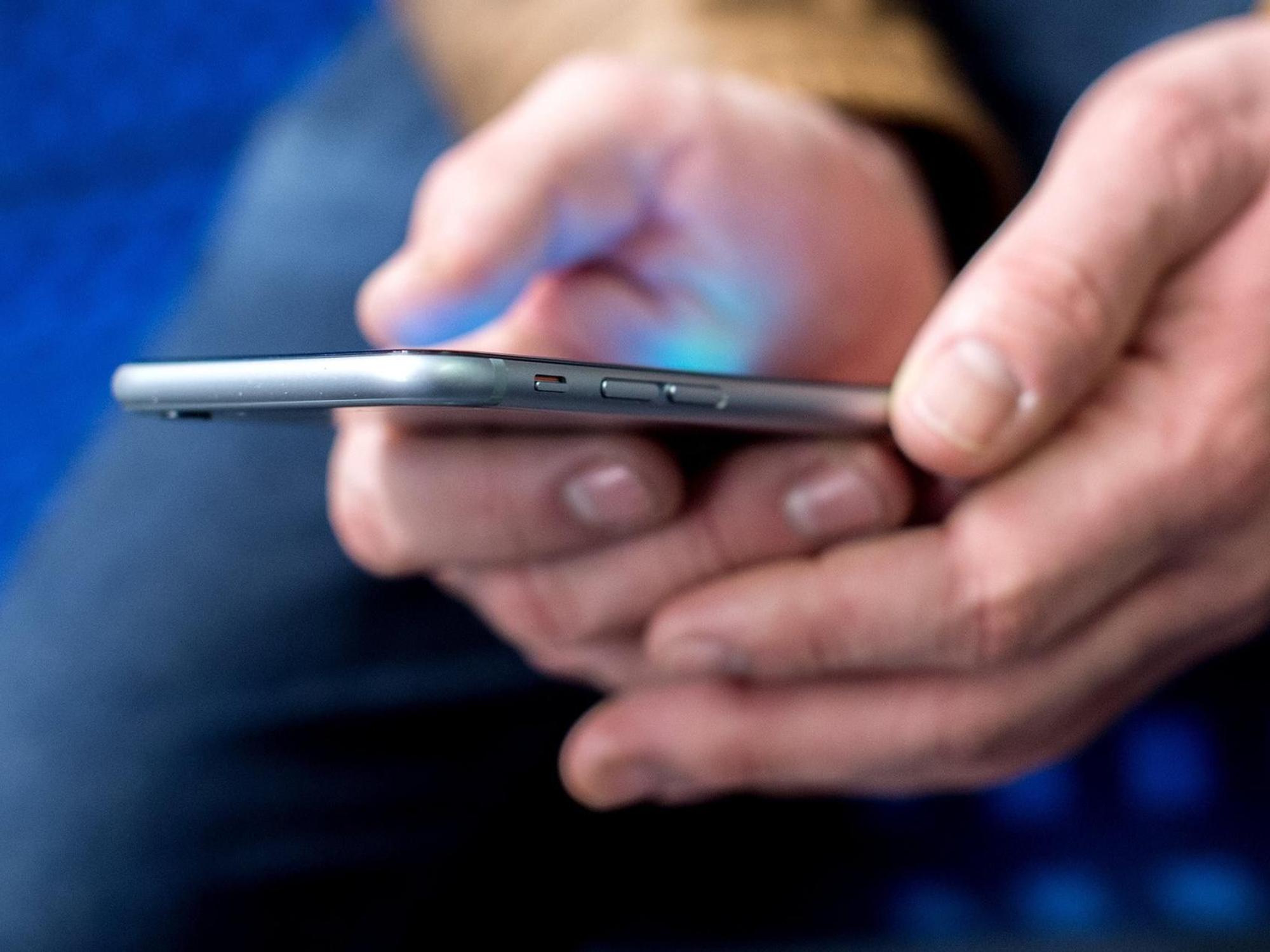 Mann hält ein Smartphone in der Hand.