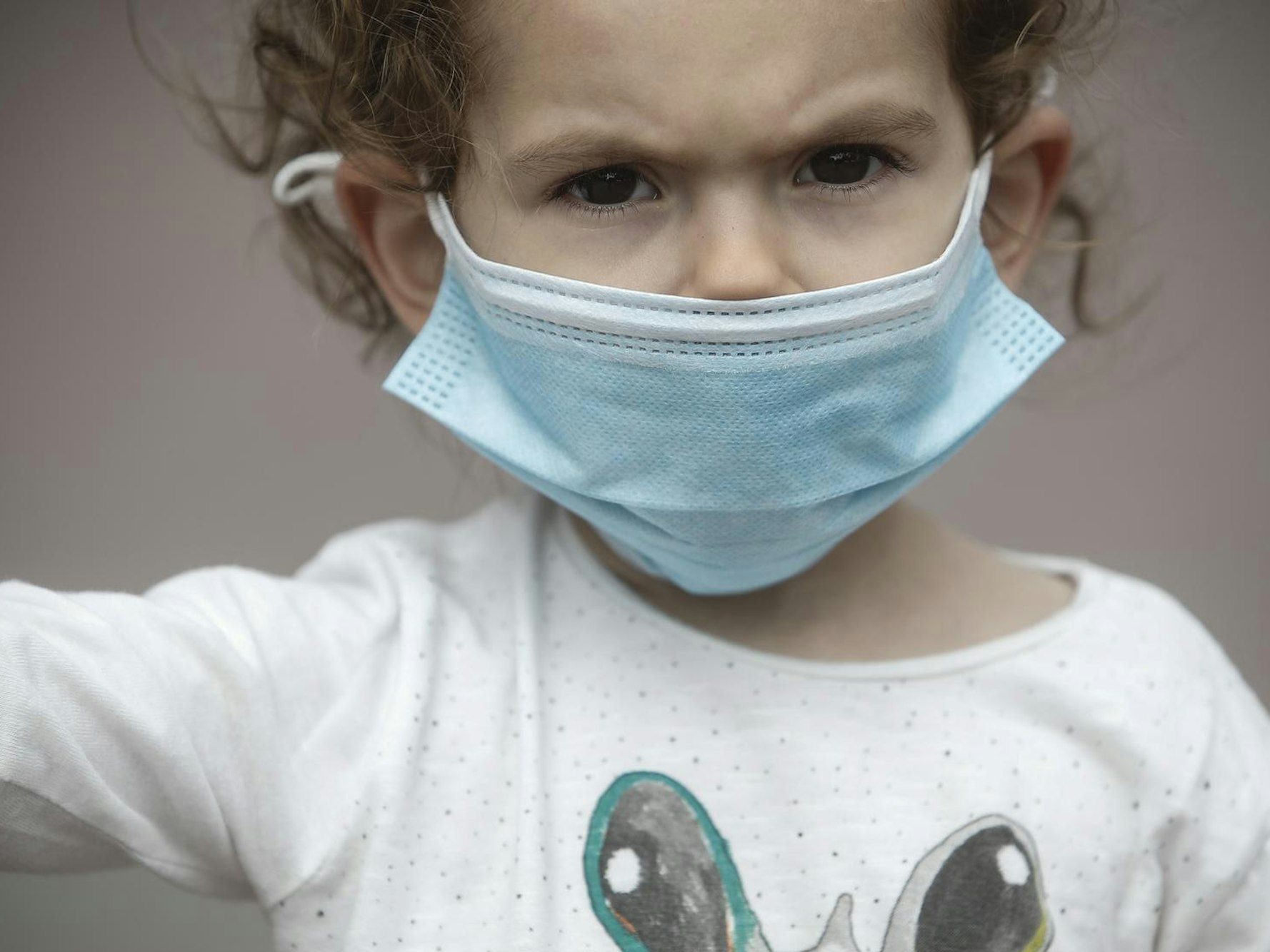 Ein Kind mit Maske - es muss vielleicht wegen Corona in Quarantäne und von der Familie isoliert werden