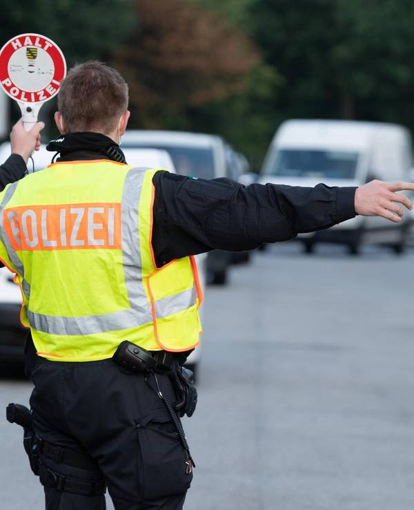 Ein Polizist winkt bei einer Kontrolle ein Auto heraus.
