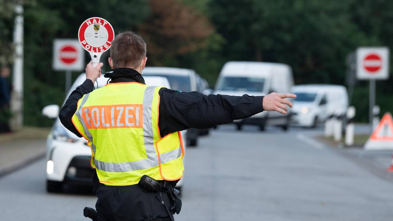 Ein Polizist winkt bei einer Kontrolle ein Auto heraus.