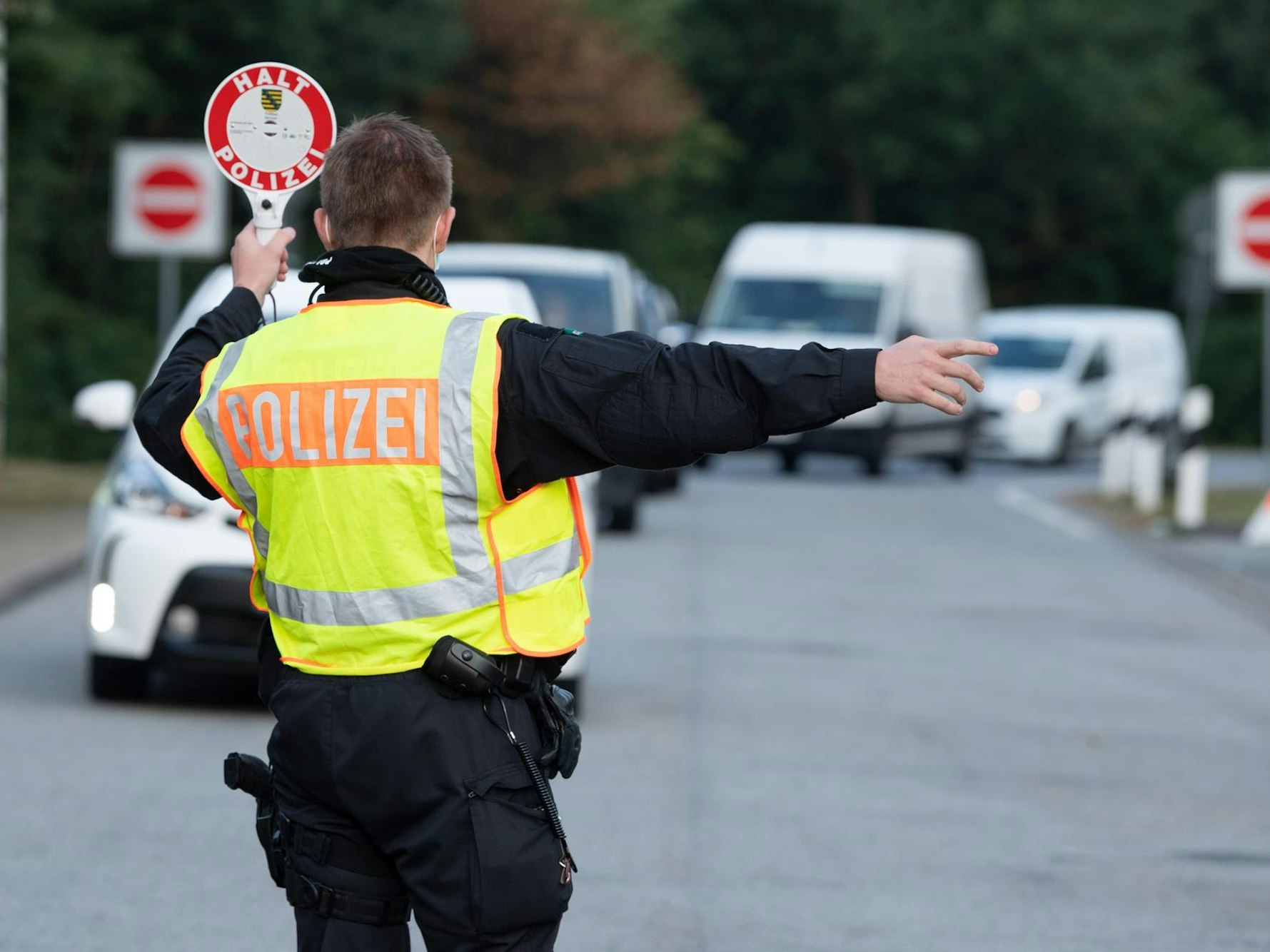 Ein Polizist winkt bei einer Kontrolle ein Auto heraus.