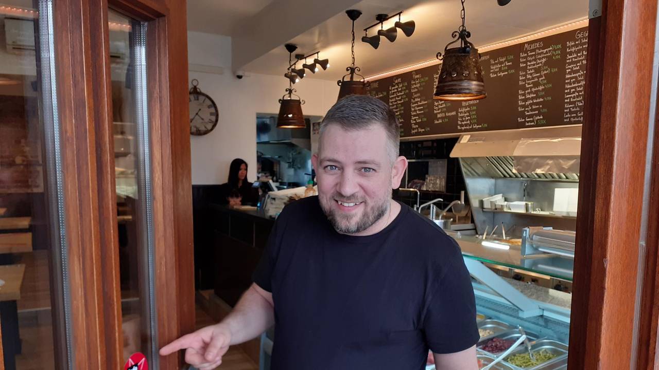 Christos Charalabidis zeigt den Jode-Lade-Sticker an seinem Laden Tischlein deck dich.