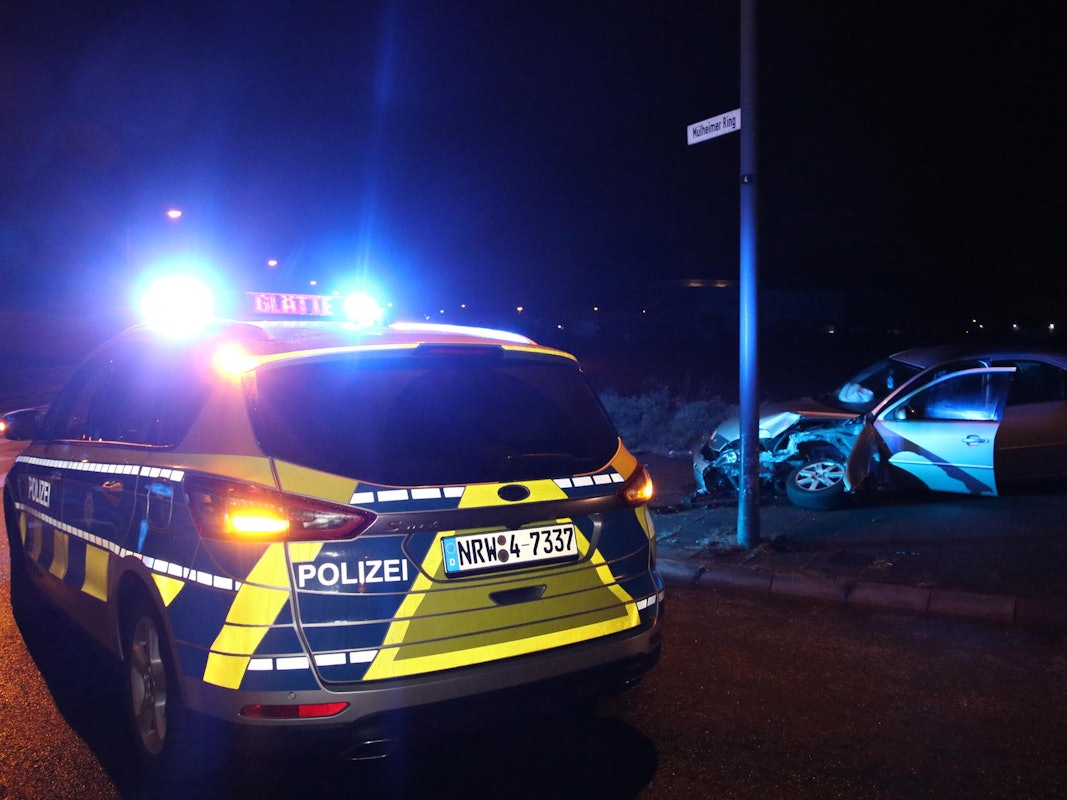 Ein Polizeifahrzeug steht neben einem völlig beschädigten Auto.
