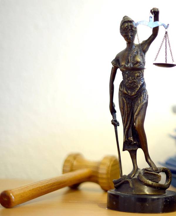 Das Modell einer Justitia neben einem Aktenstapel.