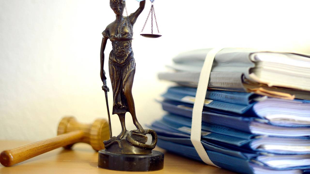 Das Modell einer Justitia neben einem Aktenstapel.