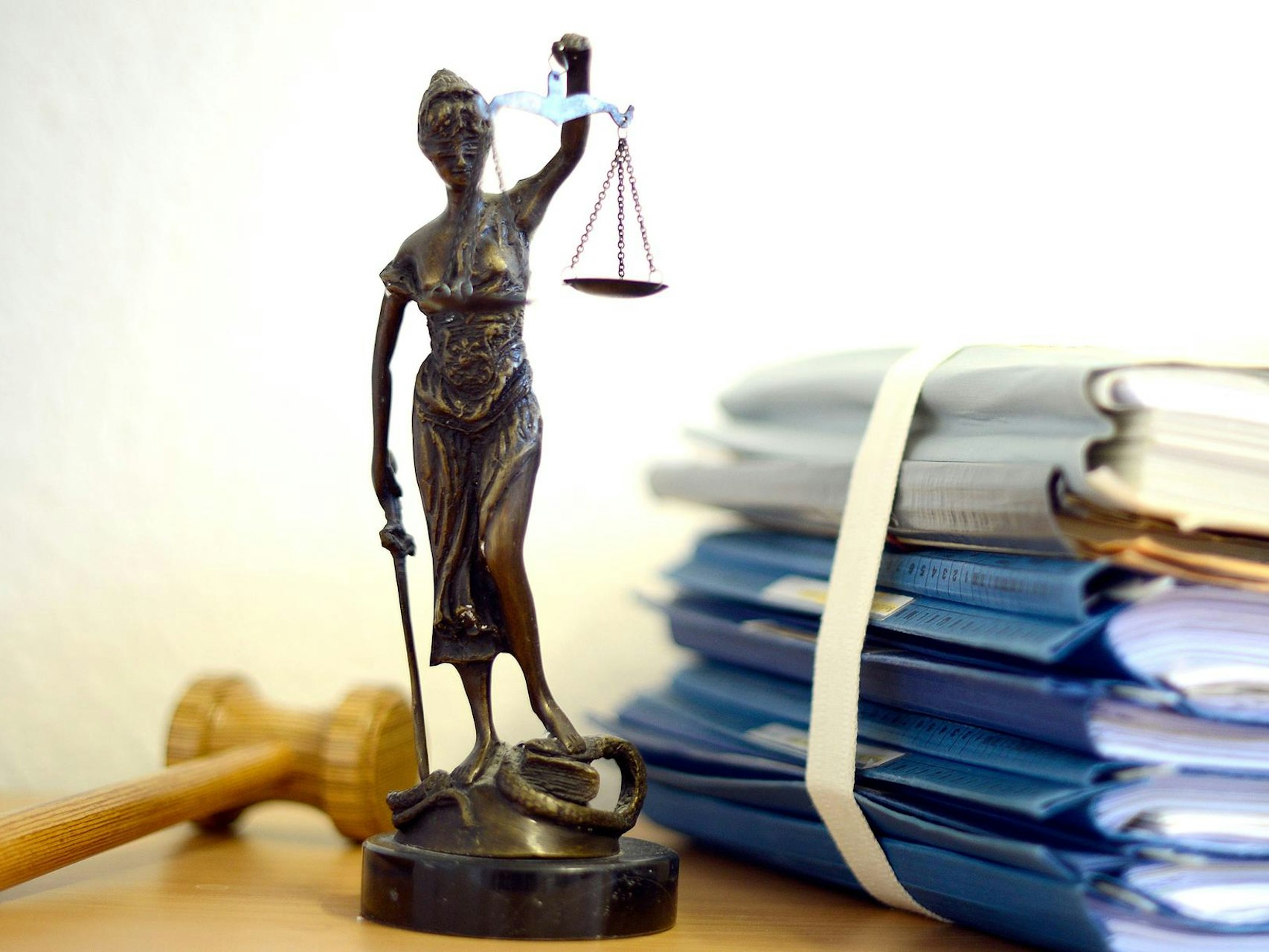 Das Modell einer Justitia neben einem Aktenstapel.