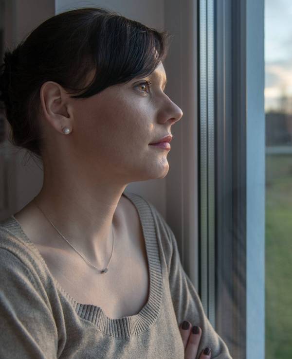 Eine Frau schaut nachdenklich aus dem Fenster.