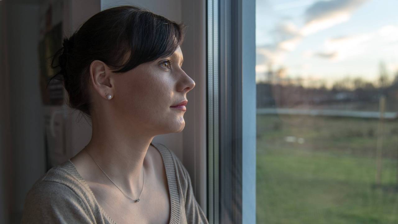 Eine Frau schaut nachdenklich aus dem Fenster.