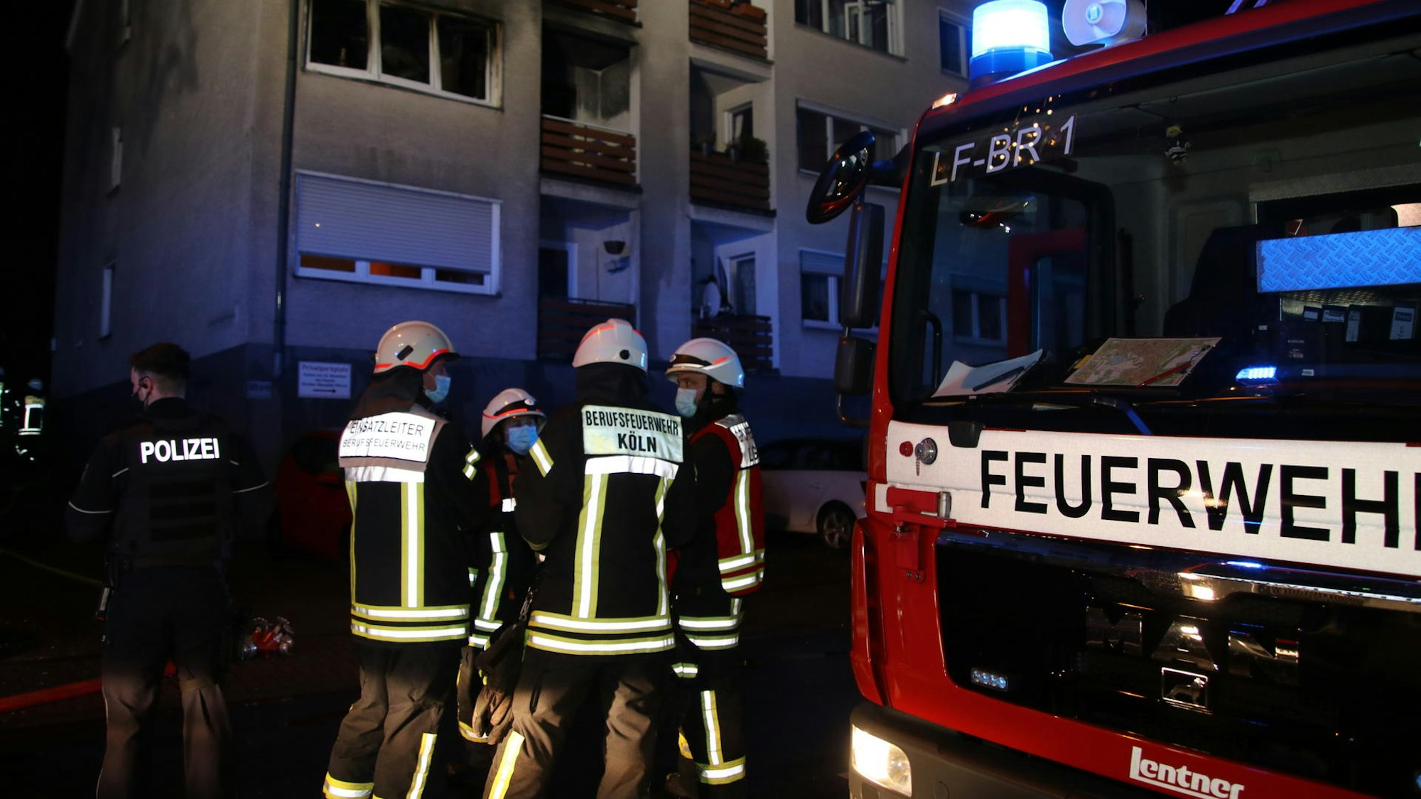 Feuerwehrmänner stehen neben einem Einsatzfahrzeug.