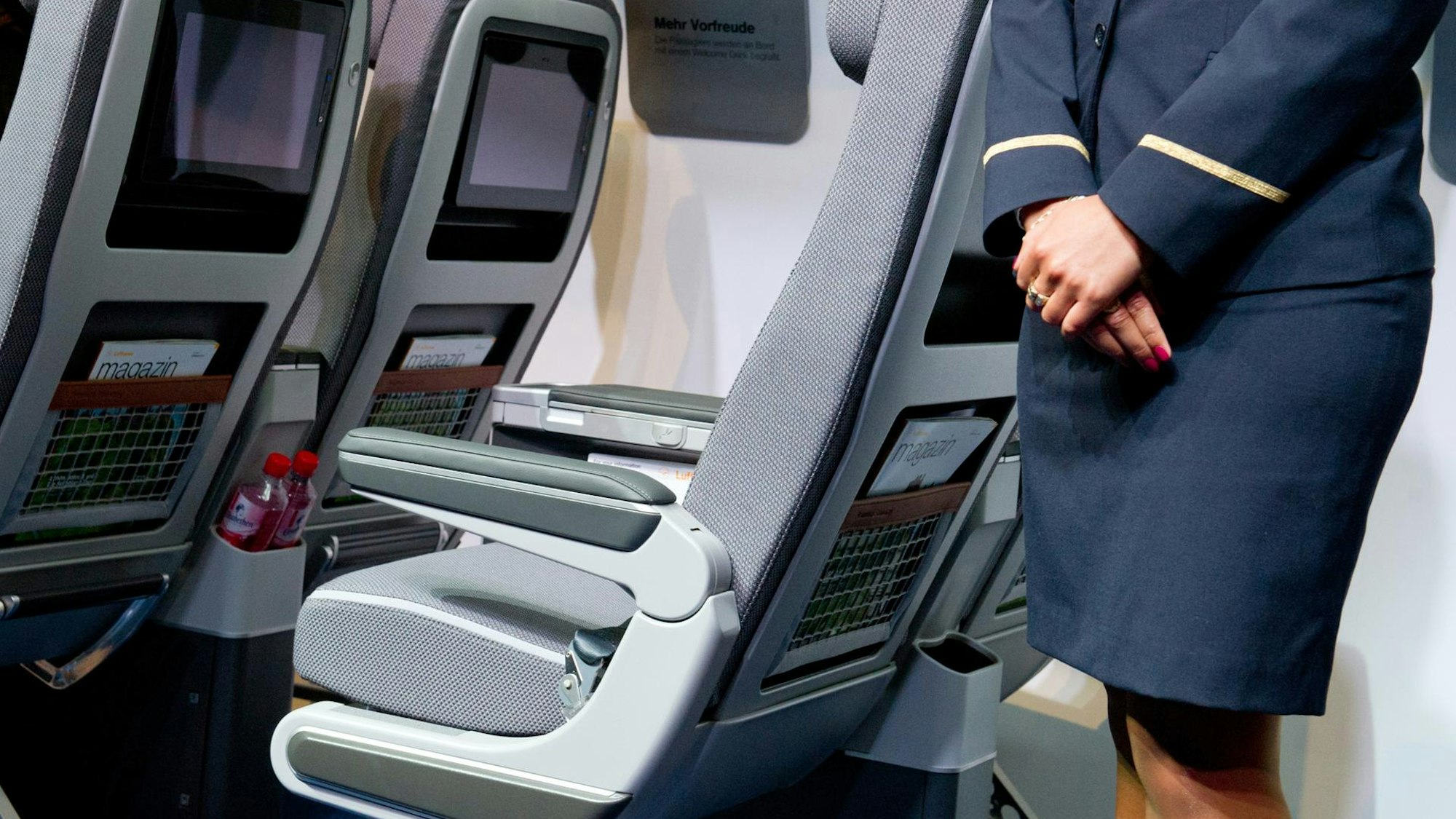 Flugbegleiterin vor Sitzen im Flugzeug