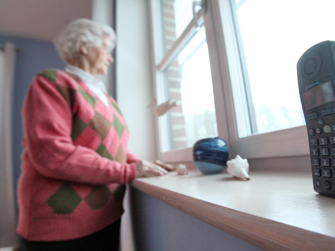 Eine Rentnerin schaut aus dem Fenster.