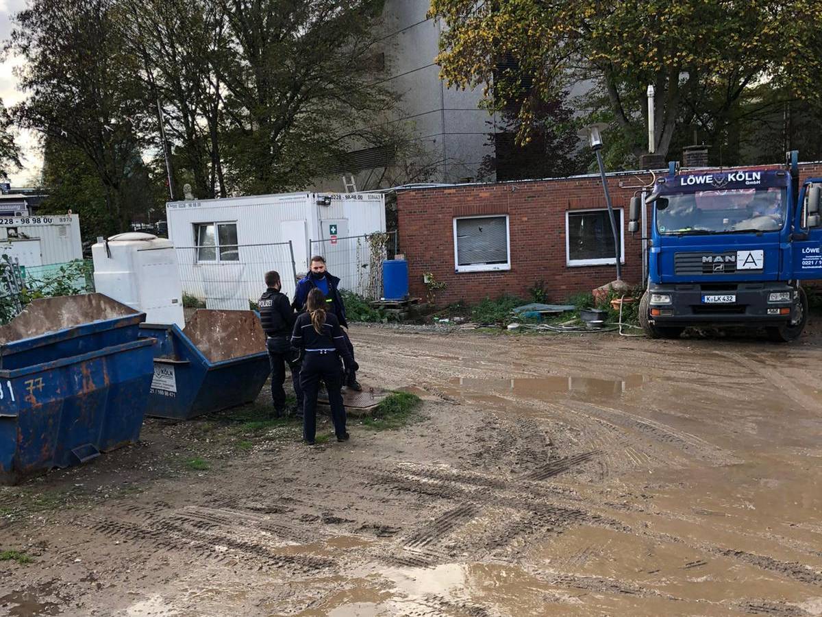 Yüksel Aker steht mit zwei Polizisten auf seinem Firmengelände in Köln.