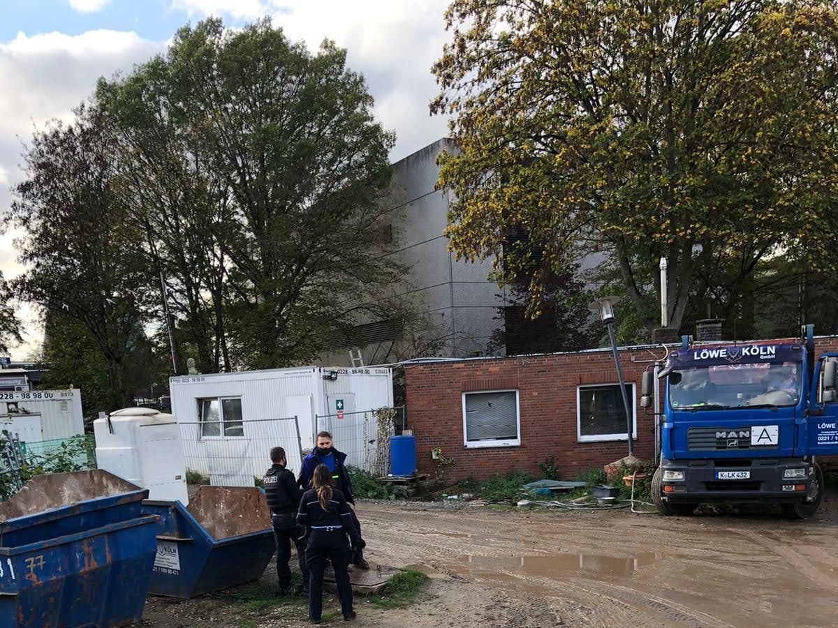 Yüksel Aker steht mit zwei Polizisten auf seinem Firmengelände in Köln.