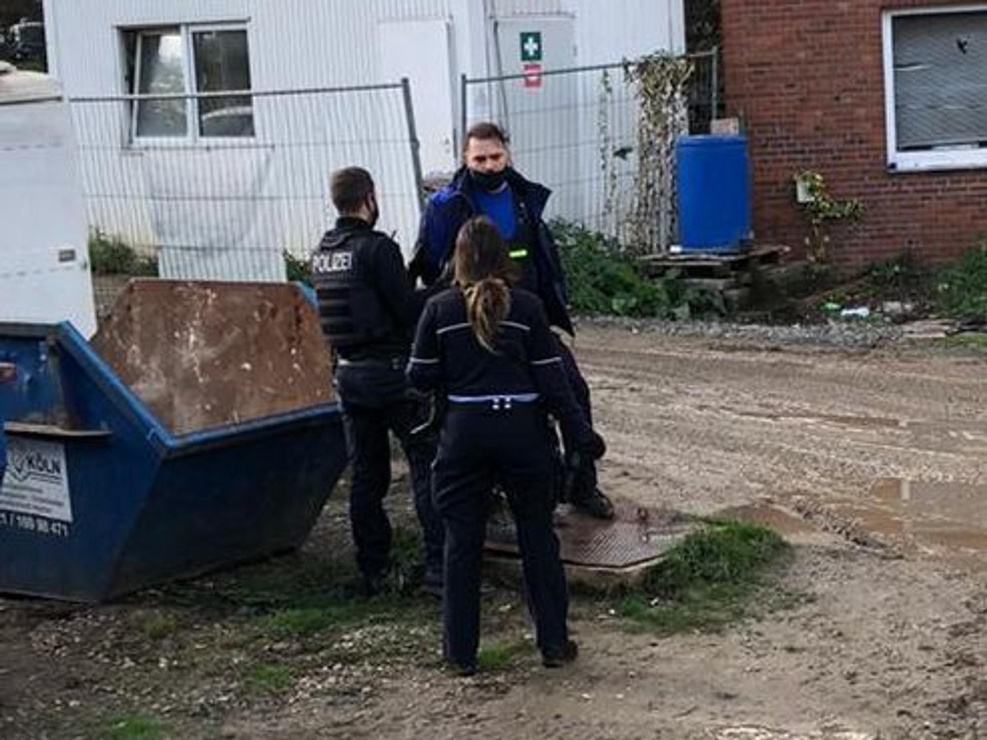 Yüksel Aker steht mit zwei Polizisten auf seinem Firmengelände in Köln.