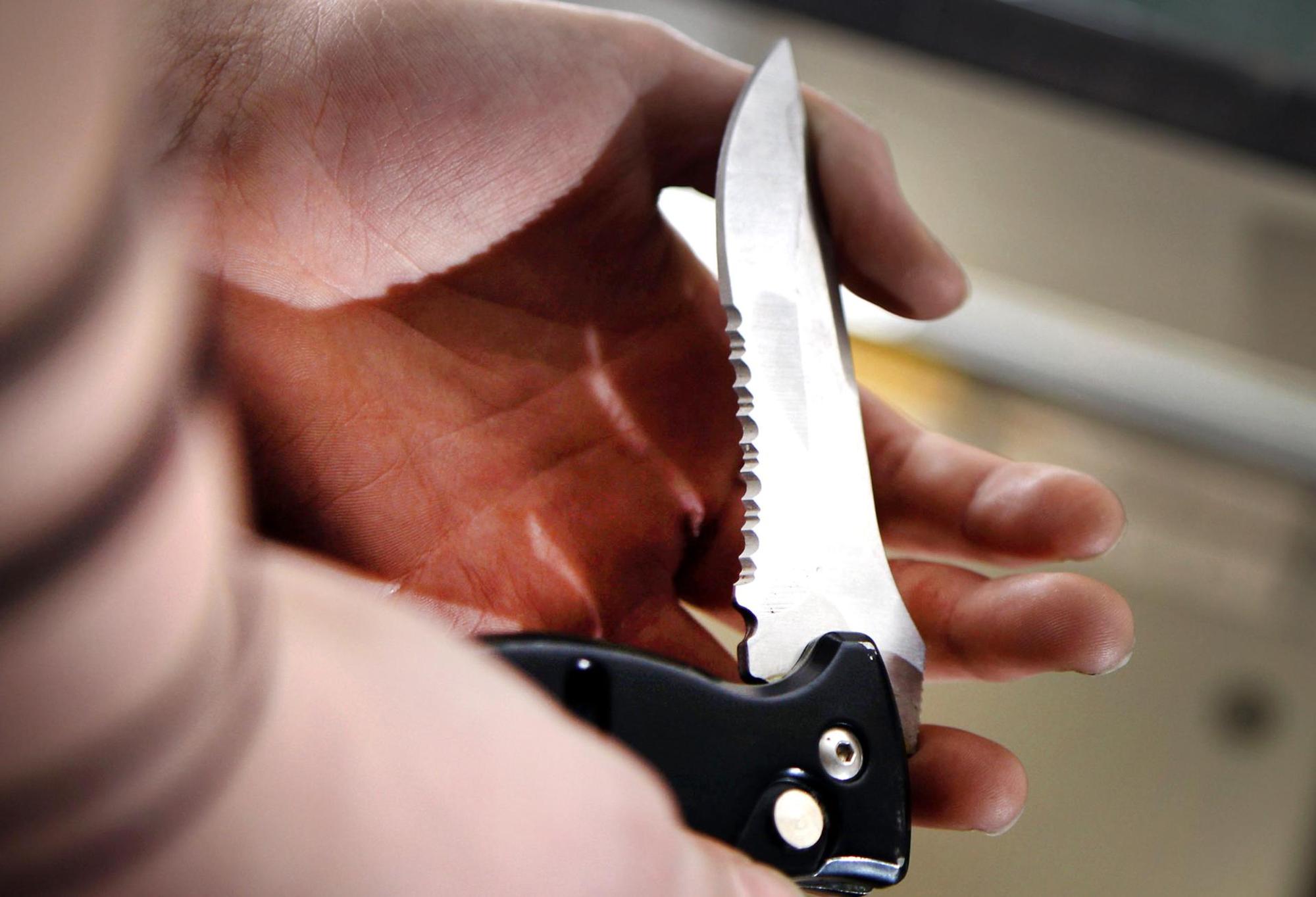 Mann hält ein Messer gezückt.