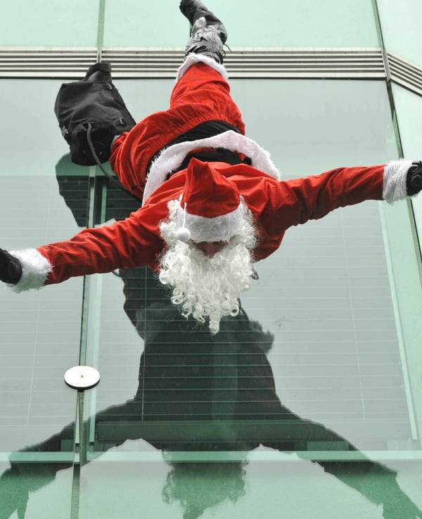 Ein Weihnachtsmann hängt kopfüber an einem Gebäude.