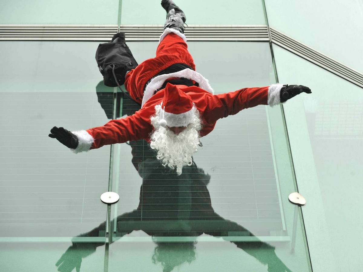 Ein Weihnachtsmann hängt kopfüber an einem Gebäude.