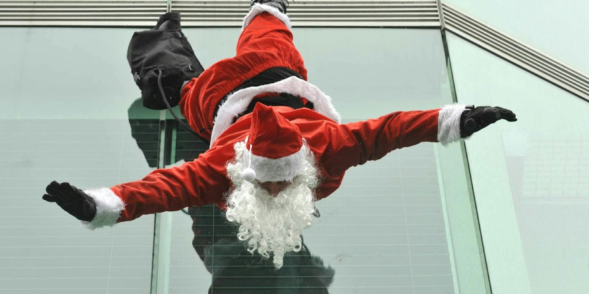 Ein Weihnachtsmann hängt kopfüber an einem Gebäude.