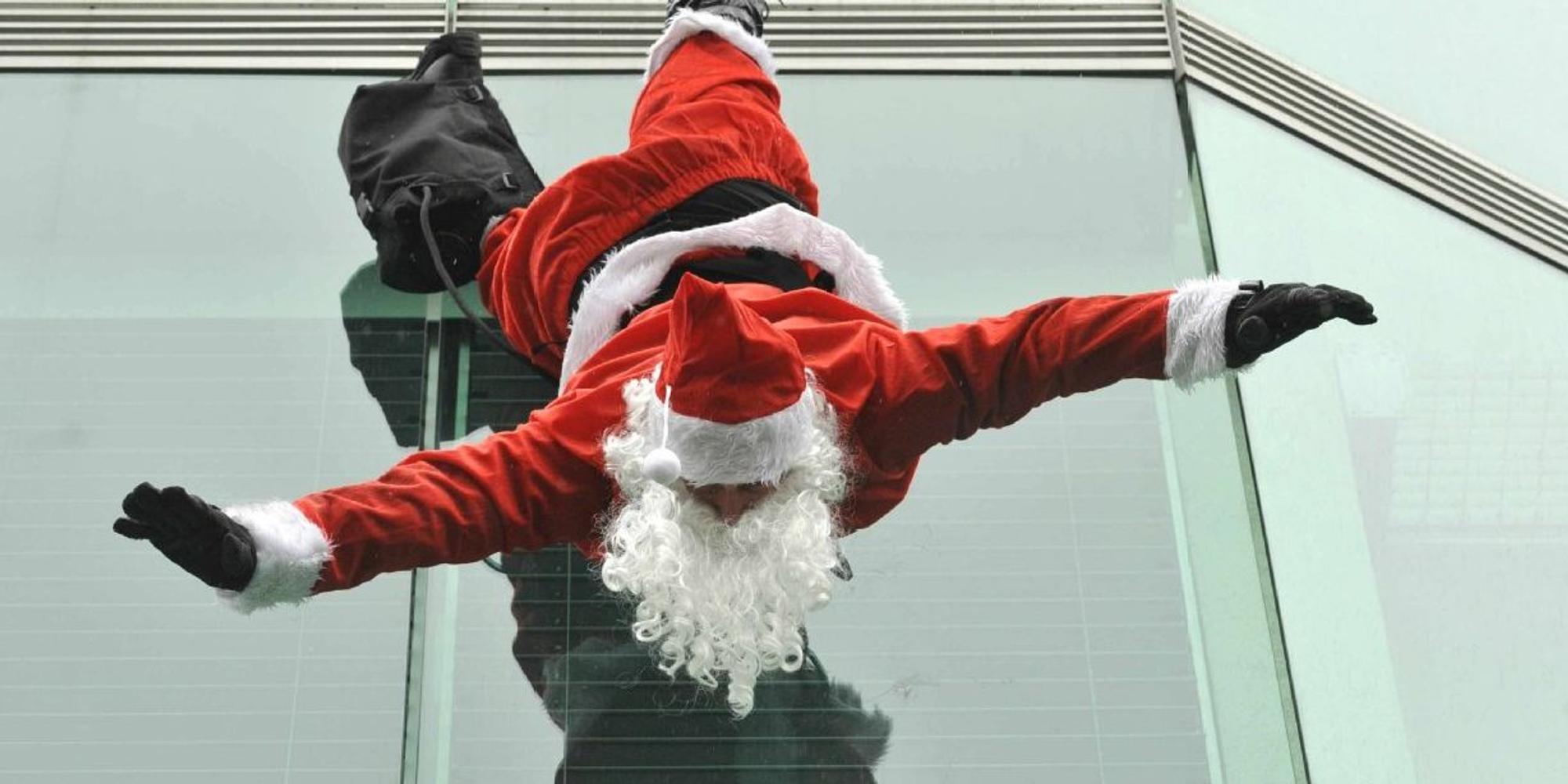 Ein Weihnachtsmann hängt kopfüber an einem Gebäude.