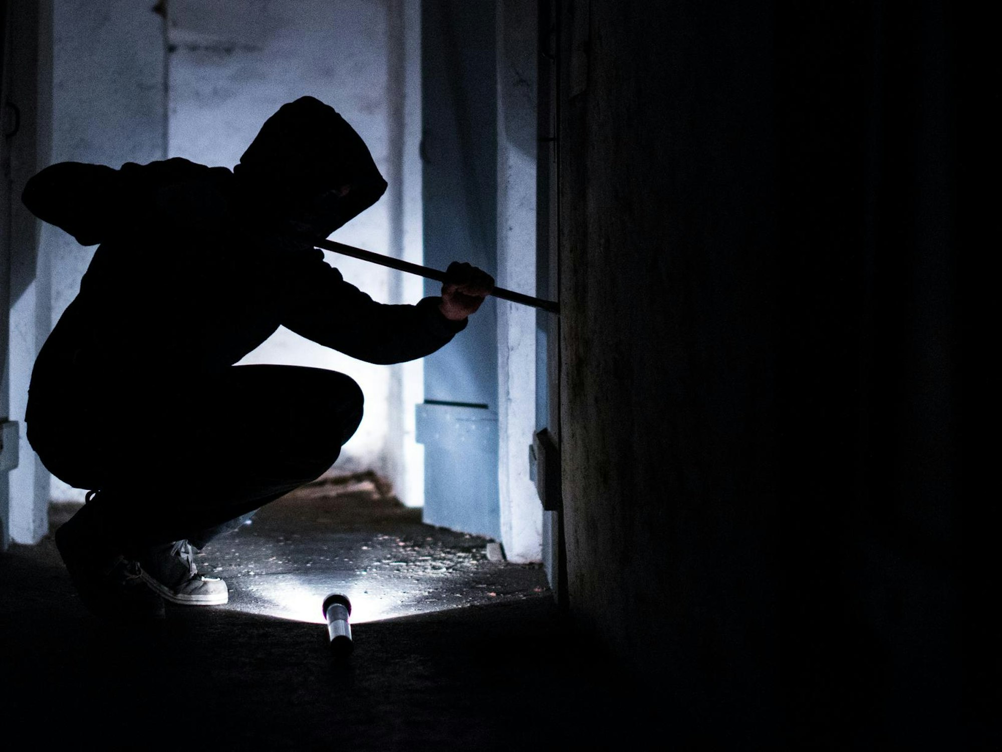 Eine Person macht sich mit einem Stemmeisen an der Tür zu schaffen.