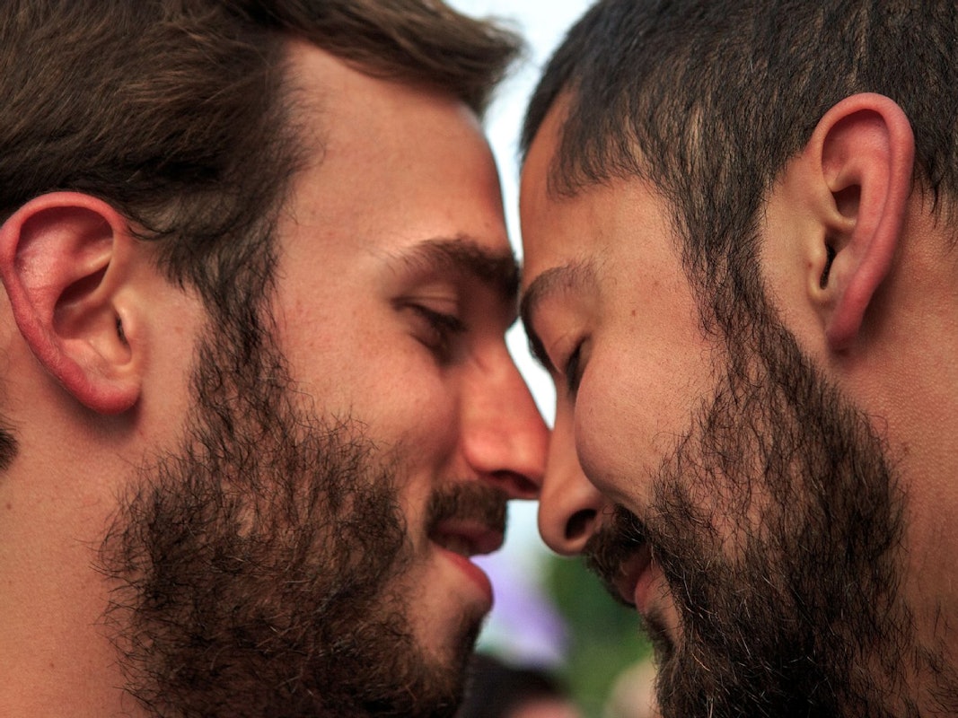 Zwei Männer, die ihre Köpfe zärtlich aneinanderlehnen.