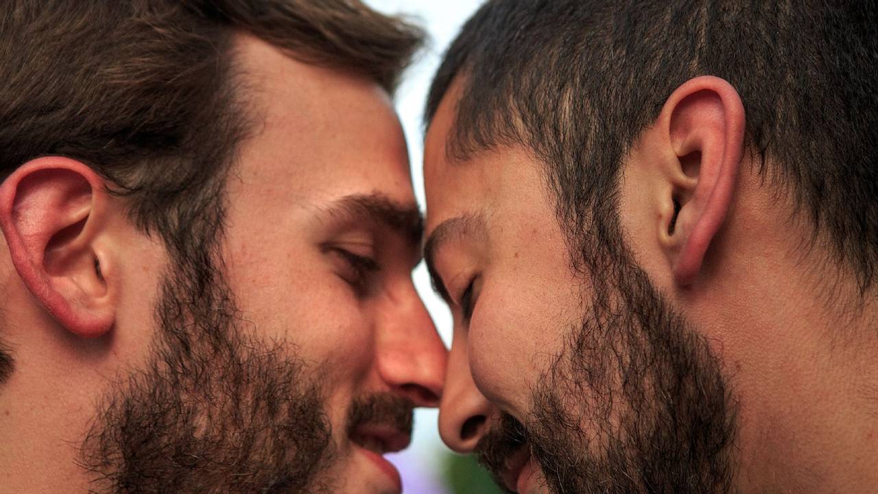 Zwei Männer, die ihre Köpfe zärtlich aneinanderlehnen.