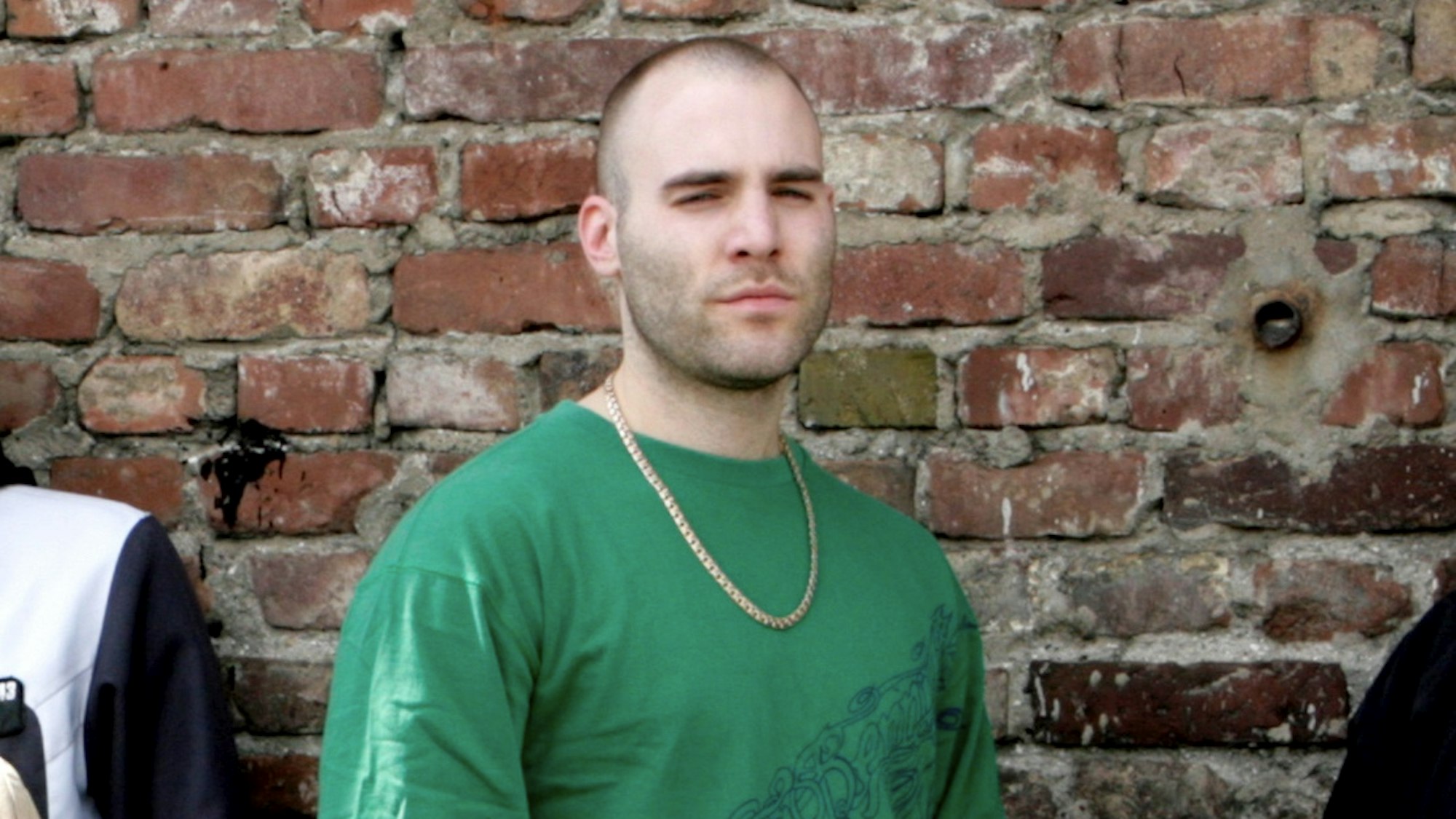 Niko B. trägt kurzgeschorene Haare und eine Goldkette um den Hals.