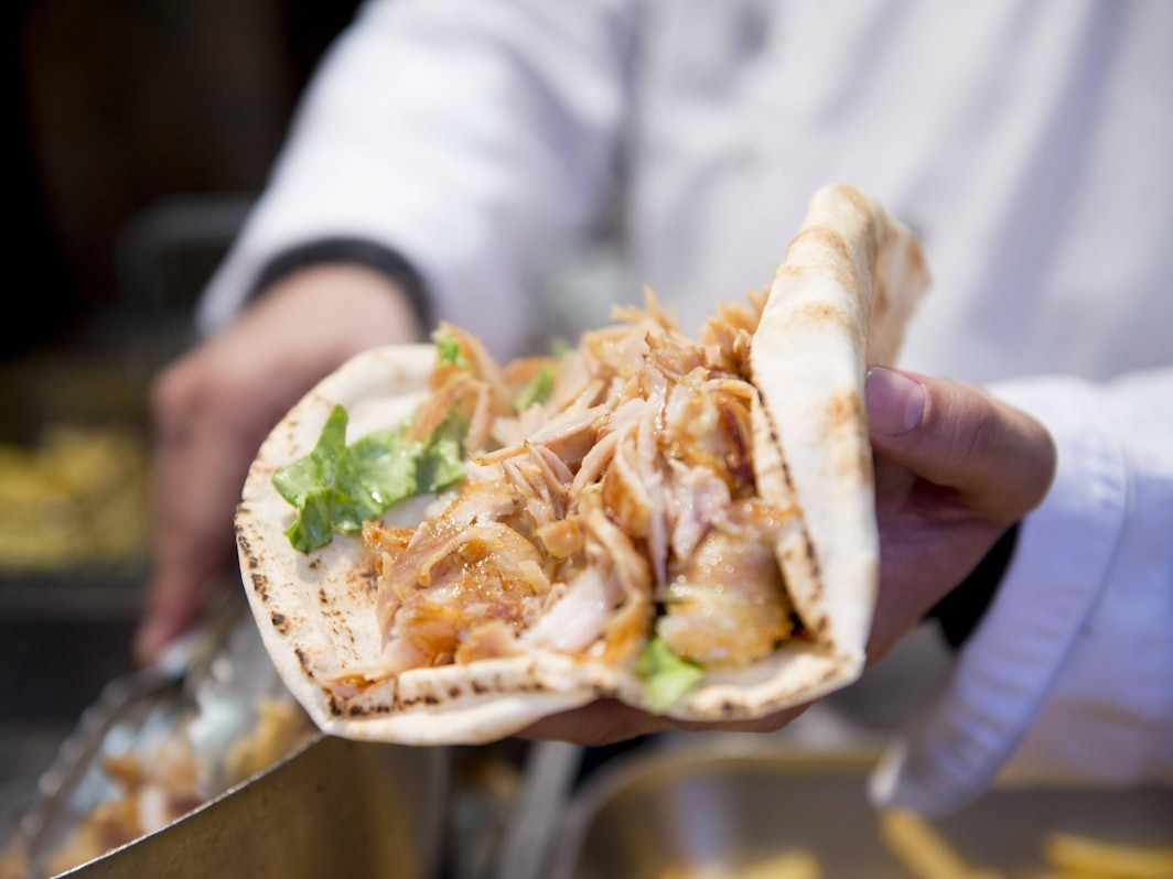 Ein Mann hält einen Döner in der Hand.