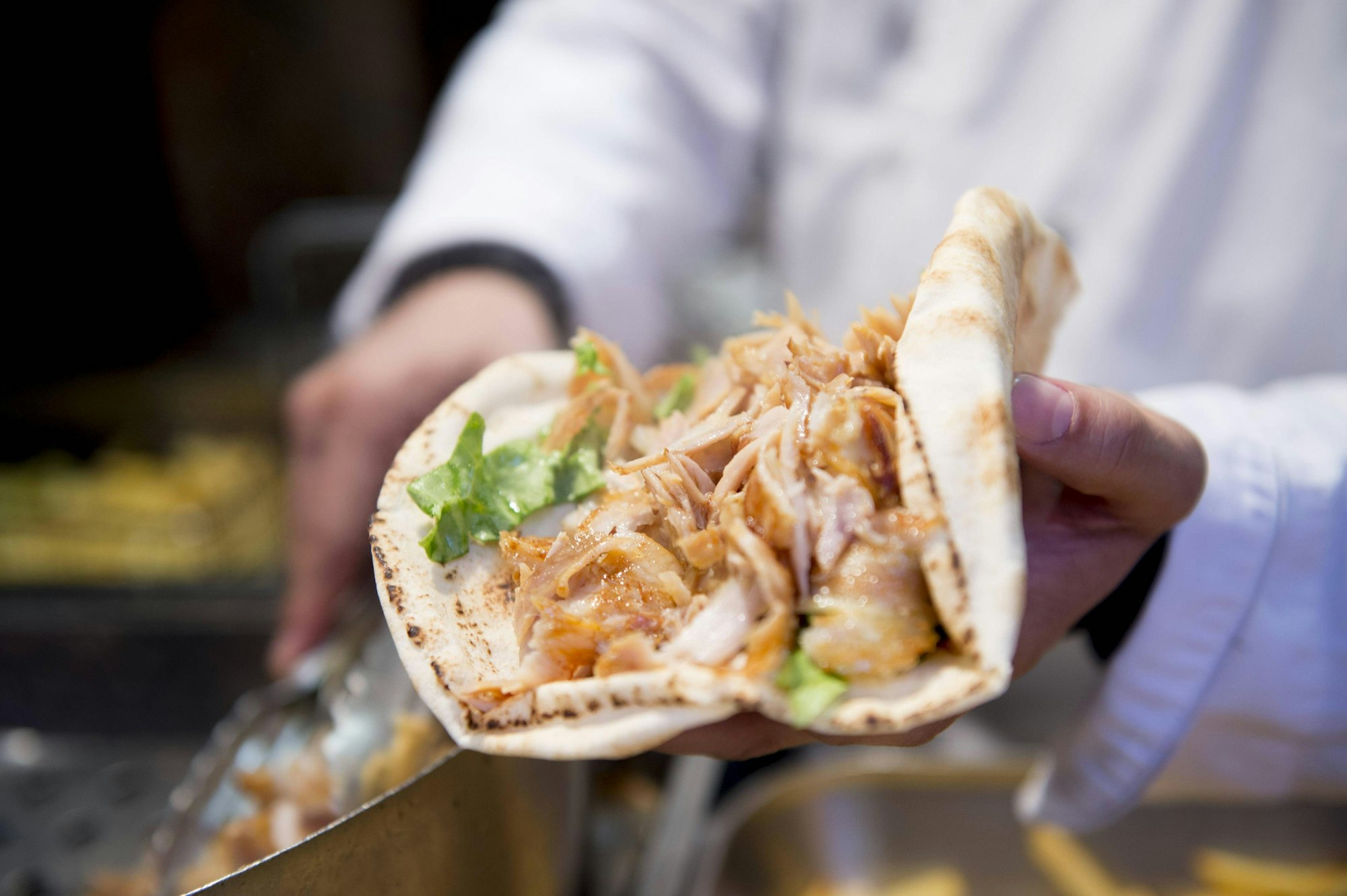 Ein Mann hält einen Döner in der Hand.