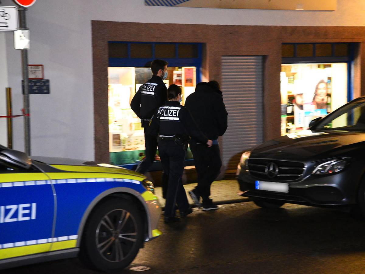 Zwei Polizisten kontrollieren einen jungen Mann.