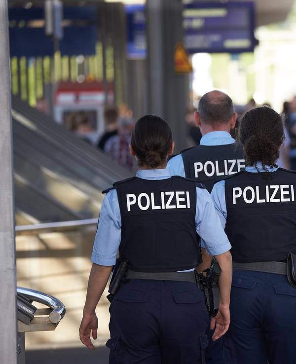 Polizisten gehen an einem Bahnsteig entlang.